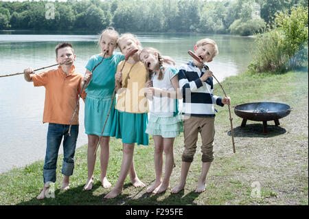 Gruppe von Freunden essen Würstchen mit Brot am See, Bayern, Deutschland Stockfoto