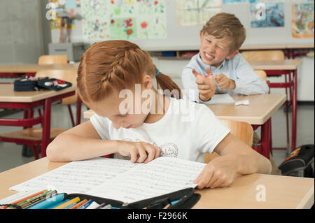 Schuljunge stört ein Schulmädchen mit Schleuder im Klassenzimmer, München, Bayern, Deutschland Stockfoto