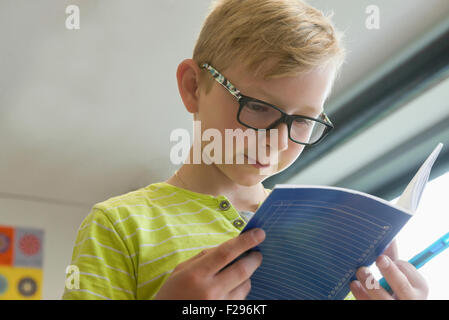 Schuljunge, der ein Buch im Klassenzimmer liest, München, Bayern, Deutschland Stockfoto