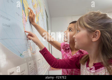 Schülerinnen studieren eine Weltkarte im Klassenzimmer in München, Bayern, Deutschland Stockfoto