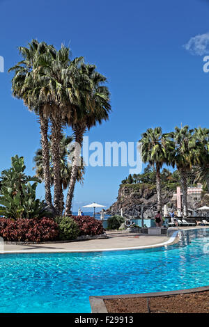 Swimming Pool und Palmen, legen Sie gegen einen herrlichen blauen Himmel Stockfoto