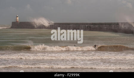 Newhaven, East Sussex, Großbritannien. September 2015. Ein trübes, sehr blutriger Tag an der Küste mit einigen hellen Intervallen. Surfer vor West Beach, wenn Wellen über dem Arm abstürzen. Stockfoto