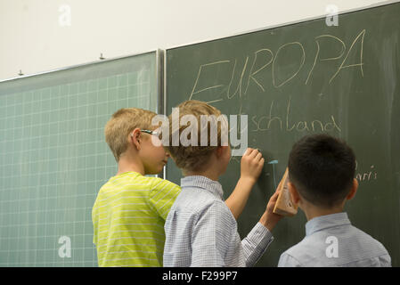 Schüler schreiben an Tafel im Klassenzimmer, München, Bayern, Deutschland Stockfoto