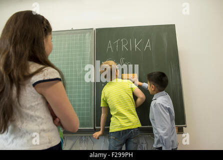 Schuljungen, die an der Tafel schreiben und ihre Klassenkameraden, die sie anschauen, München, Bayern, Deutschland Stockfoto