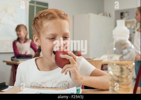 Nahaufnahme einer Schülerin Essen eines Apfels im Klassenzimmer, München, Bayern, Deutschland Stockfoto