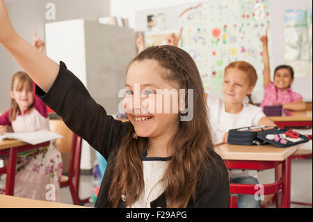Schulkinder mit erhobenen Händen im Klassenzimmer, München, Bayern, Deutschland Stockfoto
