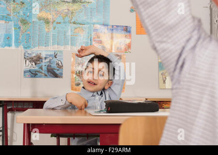 Schulkinder mit erhobenen Händen im Klassenzimmer, München, Bayern, Deutschland Stockfoto