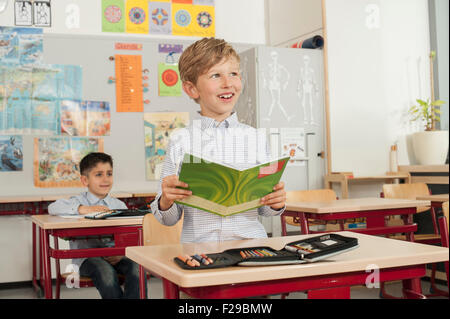 Schuljunge, der ein Buch im Klassenzimmer liest, München, Bayern, Deutschland Stockfoto