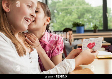 Schülerinnen flüstern im Klassenzimmer und zeigen einen Liebesbrief, München, Bayern, Deutschland Stockfoto