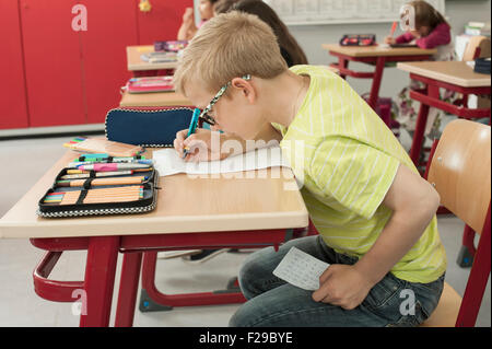 Schuljunge betrügt bei einem Test im Klassenzimmer, München, Bayern, Deutschland Stockfoto