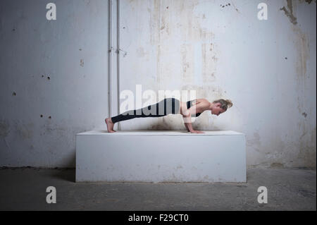 Mitte Erwachsene Frau üben Plank Pose auf Betonblock, München, Bayern, Deutschland Stockfoto