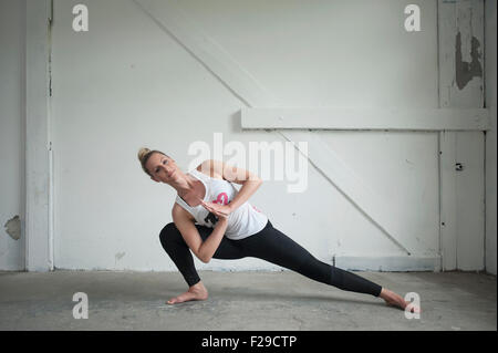 Mitte Erwachsene Frau üben Parighasana Pose im Yoga-Studio, München, Bayern, Deutschland Stockfoto