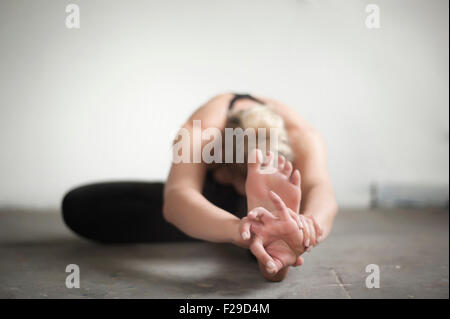 Mitte Erwachsene Frau üben Janu Sirsasana Pose im Yoga-Studio, München, Bayern, Deutschland Stockfoto