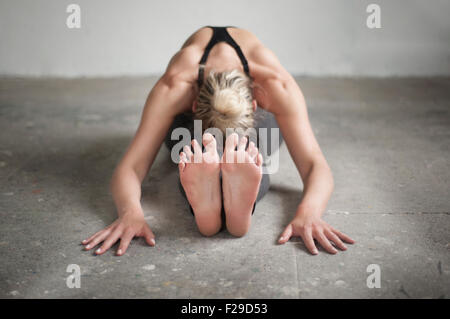 Mitte Erwachsene Frau üben sitzend nach vorne beugen Pose im Yoga-Studio, München, Bayern, Deutschland Stockfoto