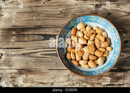 Frische Mandeln mit Schale in einer Schüssel auf einem rustikalen Tisch. Stockfoto