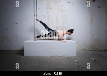 Mitte Erwachsene Frau üben Plank Pose auf Betonblock, München, Bayern, Deutschland Stockfoto