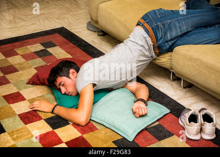 Betrunken schönen jungen Mann auf der Couch im Wohnzimmer mit Kopf auf dem Boden ruhen. Stockfoto