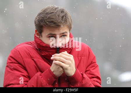 Mann im kalten Winter Schüttelfrost und rieb sich die Hände, während schneit Stockfoto