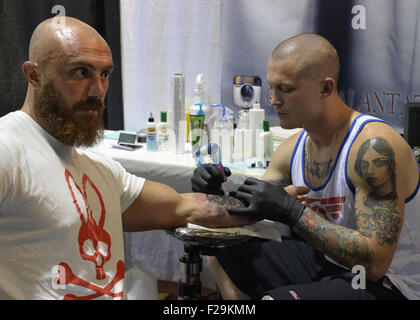 Garden City, New York, USA. 13. Sep, 2015. LUKE PALAN, ein Tattoo-Künstler aus Las Vegas, ist ein Mann Arm auf der United Tinte Flug 915 Tattoo Convention im Cradle Aviation Museum in Long Island tätowieren. Der bärtige Mann ist ein Psycho-Hase weißen und roten t-Shirt. © Ann Parry/ZUMA Draht/Alamy Live-Nachrichten Stockfoto
