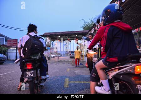 Cheras, Malaysia. 15. Sep, 2015. Ein Angestellter einer Schule Gesten, Patriarchen Motorradfahren mit ihren Kindern über der Schule der Tages-Schliessung in Cheras Selangor, Malaysia, 15. September 2015 zu informieren. Schulen in Malaysias Hauptstadt und mehrere Staaten haben gesagt, inmitten der sich verschlechternden Dunst aus dem benachbarten Indonesien am Dienstag geschlossen. © Chong Voon Chung/Xinhua/Alamy Live-Nachrichten Stockfoto