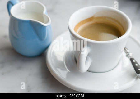 Verschwommene Sicht auf Kaffee und Krug Milch Stockfoto