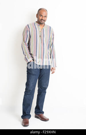Voller Länge sicher Reifen indischen Mann in Freizeitkleidung auf einfarbigen Hintergrund mit Schatten stehen.