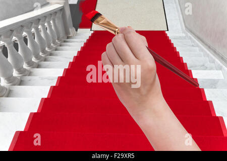 Kunst-Konzept - Hand mit Pinsel malt roten Teppich auf weiße Marmortreppe Stockfoto