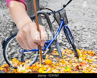Natur-Konzept - Hand mit Pinsel malt gelbe Herbstlaub auf städtischen Straße Stockfoto