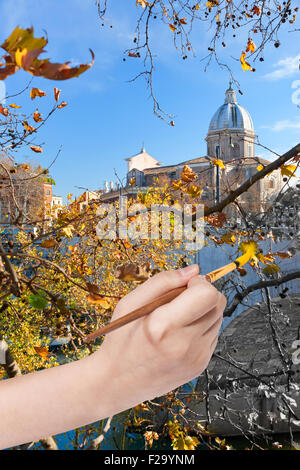 Reisekonzept - Hand mit Pinsel malt gelbe Blätter an Uferpromenade in Rom, Italien Stockfoto