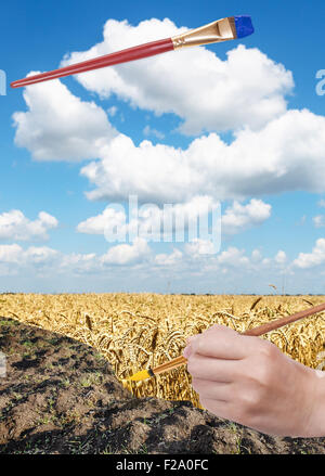 Ernte Konzept - Hand mit Pinsel malt gelbe Ernte im Frühjahr gepflügtes Feld Stockfoto