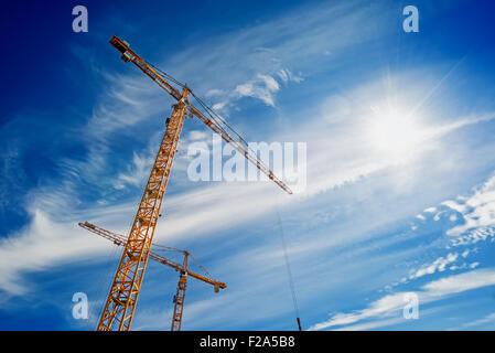 Zwei gelbe Industriekrane arbeitet auf Baustelle gegen blauen Himmel Stockfoto
