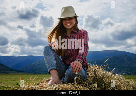 Mädchen sitzen auf einem Heuhaufen in einem Feld Stockfoto