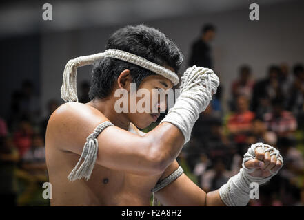 Muay thai Kämpfer auf einer Muai-Thai Gala in Bangkok, Thailand. Er trägt eine traditionelle Outfit und führt in eine Kampfkunst-Show. Stockfoto