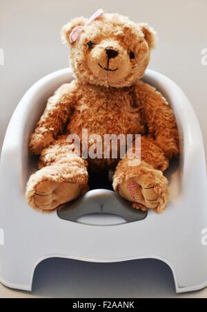 Ein Teddy sitzt auf einem Töpfchen nachweisen Toilettentraining Stockfoto