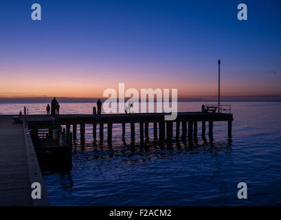 Silhouetten von Menschen stehen auf einem Pier bei Sonnenuntergang, Victoria, Australien Stockfoto