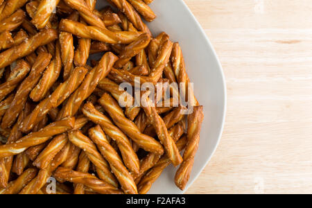 Enge Draufsicht auf einen Teller gefüllt mit geflochtener Brezeln auf einer hölzernen Tischplatte mit natürlichem Licht beleuchtet. Stockfoto