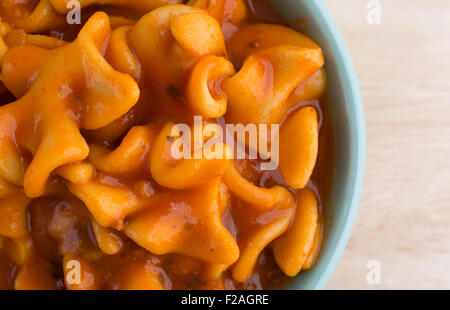 Enge Draufsicht einer Portion Dose Pasta Lasagne in einer grünen Schale auf einer hölzernen Tischplatte mit natürlichem Licht beleuchtet. Stockfoto