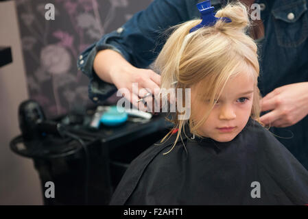 Weibliche Friseur schneiden und Bürsten Kind blondes Mädchen Haare im Friseursalon Stockfoto