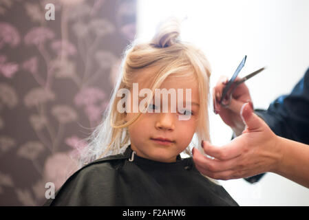 Weibliche Friseur schneiden und Bürsten Kind blondes Mädchen Haare im Friseursalon Stockfoto