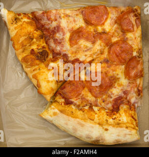 Draufsicht auf zwei Scheiben Salami Pizza in einem kleinen Karton. Stockfoto