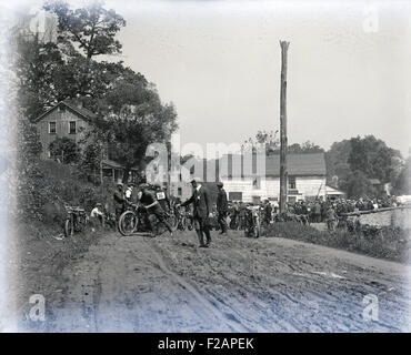 Antike ca. 1910 Foto, Teilnehmer an einem frühen Motorradrennen in einer kleinen Stadt mit schlammigen Straßen. Lage, USA. Stockfoto