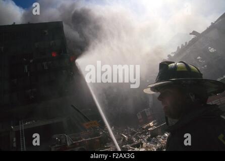 Feuerwehrmann im World Trade Center Site im folgenden September 11. Terroranschlag. In der Mitte ist Hintergrund der brennenden Haufen Stockfoto