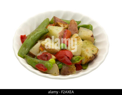 Eine Schüssel mit gerösteten Kartoffeln, Zuckerschoten und Paprika in einer Knoblauchsauce, isoliert auf einem weißen Hintergrund. Stockfoto
