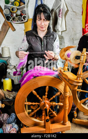 Eine Frau dreht sich mit einem traditionellen Spinnrad wolle. Stockfoto