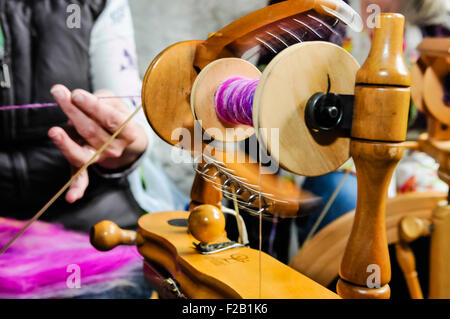 Eine Frau dreht sich mit einem traditionellen Spinnrad wolle. Stockfoto