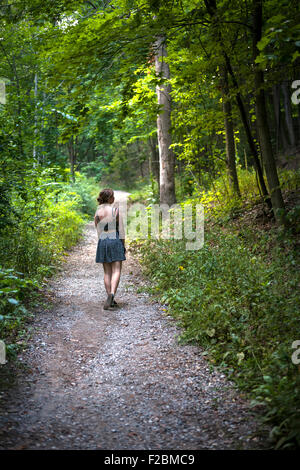 Kontemplative junge Frau Sommer Kleid stehend auf Pfad in dichten grünen Wald Stockfoto