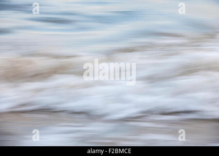 Ozean-Wellen, die am Sandstrand abstrakte, in der Kamera-Bewegung zu verwischen. Stockfoto