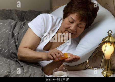 Nahaufnahme der älteren Frau, die Medizin aus der Flasche, während im Bett. Krank-Konzept. Stockfoto