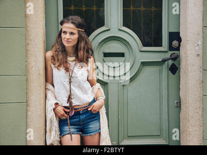 Outdoor-Mode-Porträt von trendigen Hipster junge Frau in Jeans Shorts, gestrickte Schal und weiße Bluse stehen im freien gegen Stockfoto