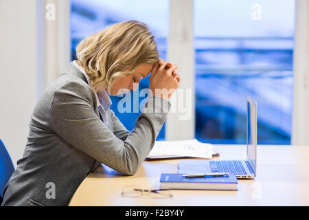 nachdenklich Geschäftsfrau sitzen im Büro, die Hände auf die Stirn Stockfoto